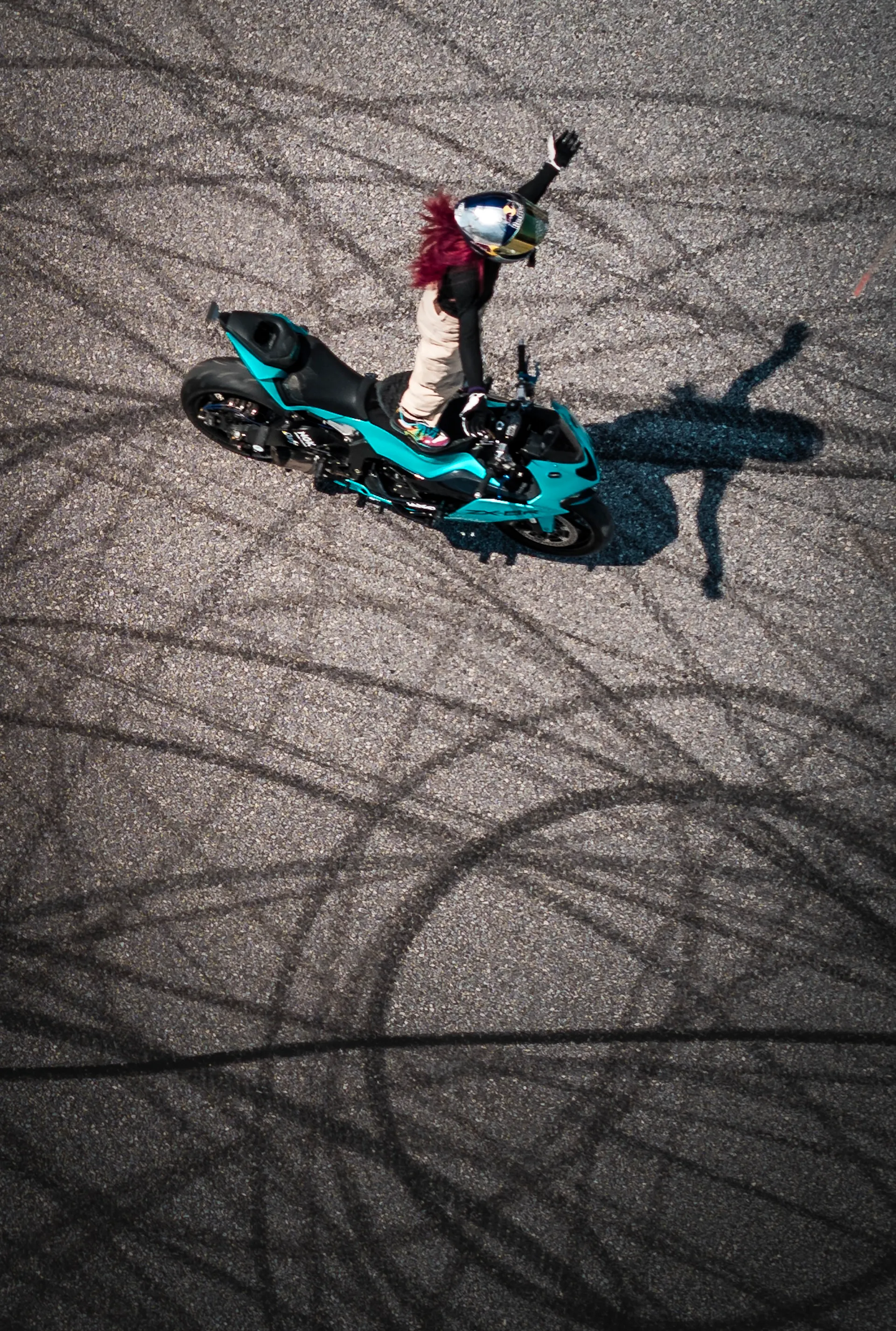 Stuntfahrerin steht auf dem Motorrad, von oben fotografiert